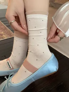 Detailed view of women mid-calf socks featuring cute black polka dots and sheer organza cuffs.