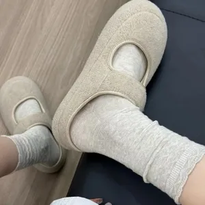 Primo piano di comode scarpe Mary Jane in pile abbinate a morbide calze di maglia grigia.