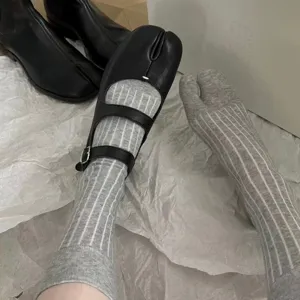 Grey vertical striped split toe socks with black Mary Jane tabi shoes, stylish streetwear look.
