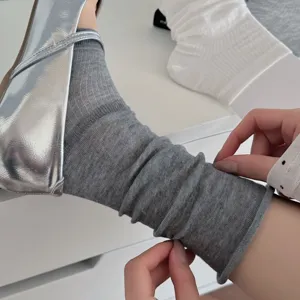 Detailed shot of grey slouch socks paired with silver ballet flats, showcasing fashion style.