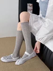 Nahaufnahme von grauen Mesh Kniestrümpfen kombiniert mit silbernen Ballerinas für Damen.