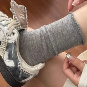 Chaussettes grises en maille ajourée avec bordure en dentelle, détail mode été doux.
