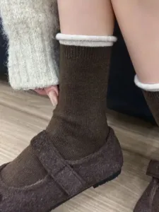 Detail view of brown winter mid-tube socks with white rolled cuff, soft and warm knit fabric.