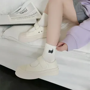 Casual white platform Mary Jane shoes paired with cute black cat embroidered white socks.