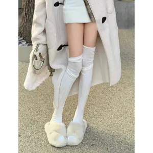 Detailed shot of solid color over-the-knee thigh high socks paired with fuzzy slippers.