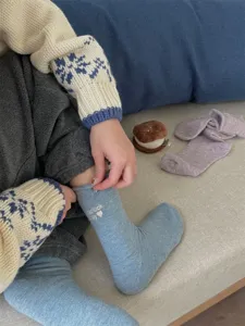 Detail view of cozy wool knit mid-tube socks featuring cute letter embroidery and soft rolled cuff.