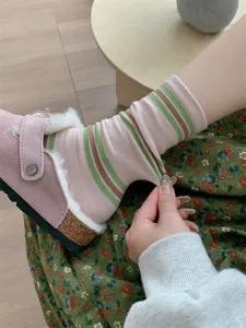 Primo piano di calzini a righe rosa e verdi, cotone morbido per uso quotidiano.