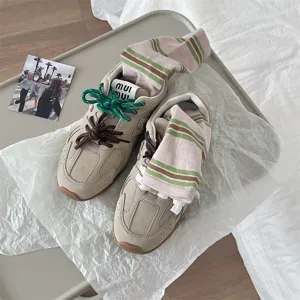Primo piano dettagliato di sneaker rétro trendy abbinate a calzini a righe colorate.