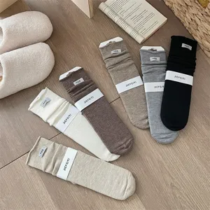 Detailed view of cozy knit stack socks in assorted solid colors with rolled cuffs and labels.