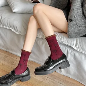 Close-up detail of women's burgundy mid-tube socks featuring cute bow prints and brown frilly cuffs.
