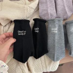 Close-up detail of cozy wool blend socks featuring cute letter embroidery and rolled cuffs.