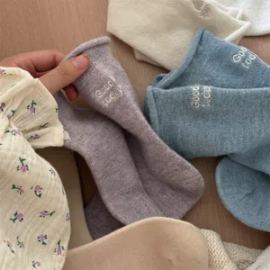 Detail shot of cozy autumn winter wool knit mid-calf socks with cute letter embroidery.