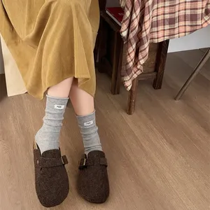 Close-up detail of grey ribbed knit slouch socks with small letter tag for women.