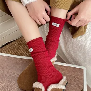 Close-up detail of women's red roll cuff stack socks with white egg label, soft cozy winter wear.