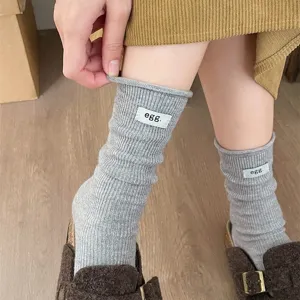 Grey ribbed slouch socks close up view, soft wool blend fabric with label detail detail shot.