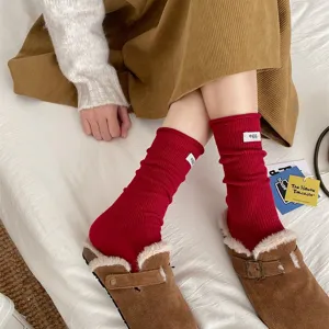 Detailed shot of red ribbed stack socks with white egg label, soft wool blend, cozy look.