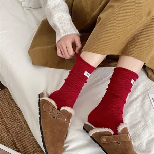 Detail view of cozy red slouch socks with tag, styled in winter lifestyle setting.