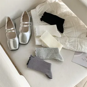 Detail view of cute ballet style socks and silver Mary Jane shoes set, soft cotton fabric.