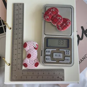 Detail shot of retro red plaid and polka dot bow hairclips with measurement rulers and scale.