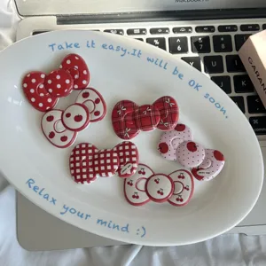 Detailed view of red plaid and polka dot bow hair clips with sweet cherry design for styling.