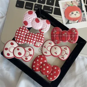 Detailed close-up of vintage red bow hair clips featuring cute cherry, apple, and polka dot designs.