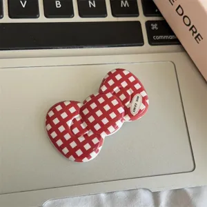 Close-up detail of a red and white plaid bow hair clip, featuring cute sweet style design.