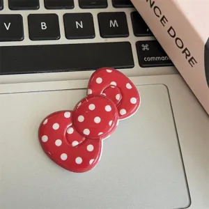 Close-up detail view of the red and white polka dot bow hair clip, cute accessory design.
