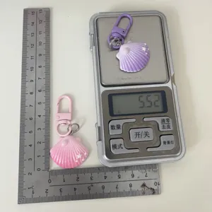 Gradient pearl shell keychain detail view, showing size and weight on scale with cute design.