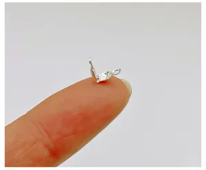 Silver tone DIY jewelry finding clamshell bead tip close up showing tiny size on finger