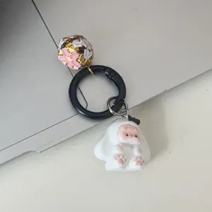 Primo piano del dettaglio portachiavi con coniglietto di peluche e campanella dorata per borsa.