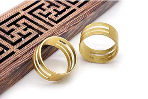Gros plan des anneaux ouverts en laiton doré avec des découpes géométriques pour vos bijoux DIY.