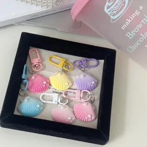 Close-up detail of pastel shell keychains with pearls and star charms in a black velvet tray.