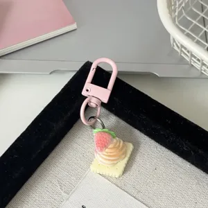 Gros plan détail du mignon porte-clés pendentif gâteau aux fraises et biscuit simulé.