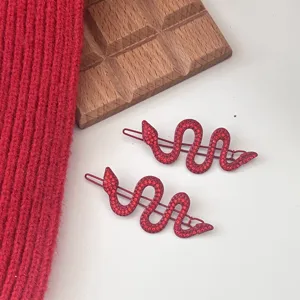 Red rhinestone snake hair clip detail, sparkling crystal bobby pin for stylish hair styling.