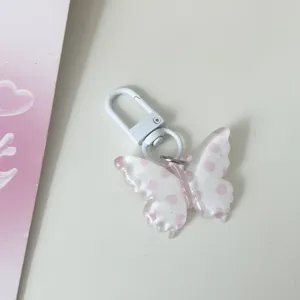Translucent pink polka dot butterfly keychain detail, cute clear bag charm pendant.