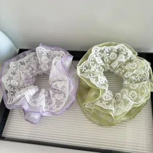 Gros plan d'élastiques à cheveux en dentelle violette et verte avec de délicates fleurs blanches.