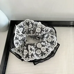Vue détaillée d'un chouchou en dentelle blanche et tulle noir avec une broderie raffinée.