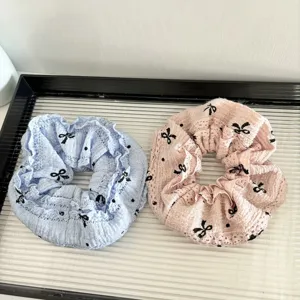 Detail view of cute lace hair scrunchies in blue and pink with cute black bow prints.