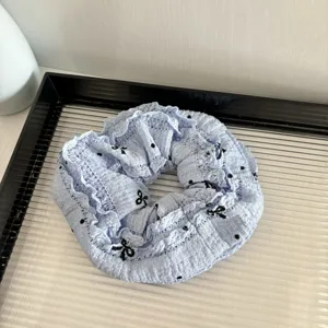 Close-up detail of light blue lace bow hair scrunchie with cute black dots for daily styling.