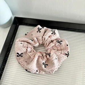 Close-up of the pink lace scrunchie with black bows, showcasing the delicate fabric details.