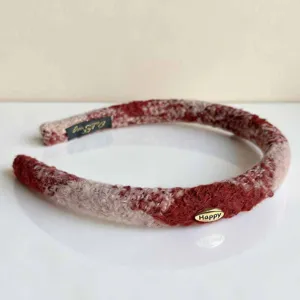 Rotes Wollhaarband Detail mit schickem metallischen Happy Etikett und weicher Strickoptik.