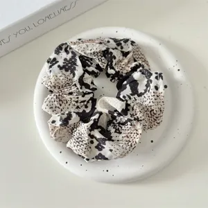 Detailed close-up of a vintage leopard print fabric scrunchie with stylish pleated design.