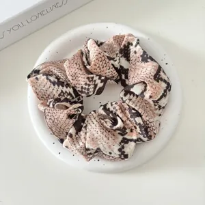Detailed view of a vintage animal print fabric hair scrunchie, wide elastic hair tie style.