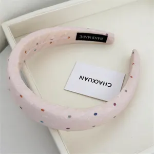 Detailed view of a cute sweet pink sponge headband decorated with colorful polka dots.