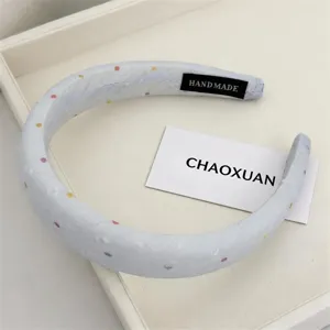 Detailed view of a light blue sponge headband with colorful polka dots, handmade hair accessory.