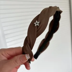 Brown braided headband detail, close up view showing star rhinestone embellishment and pleated fabric texture.