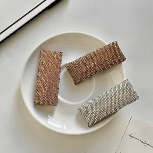 Detailed close-up view of shiny rhinestone hair clips in gold and silver, elegant fashion style.