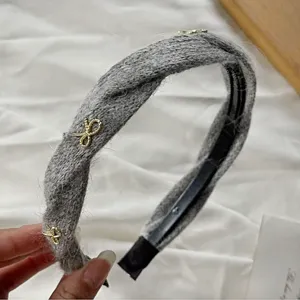 Grey knitted braided headband with cute gold bow accents, chic autumn hair accessory for women.