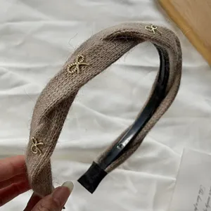 Detailed view of autumn winter knitted twist headband with cute gold bow accents, soft brown.