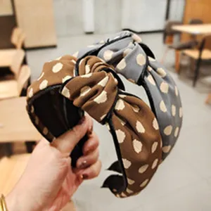 Detail view of retro polka dot knotted wide-brim headband, fashionable satin hair accessory.